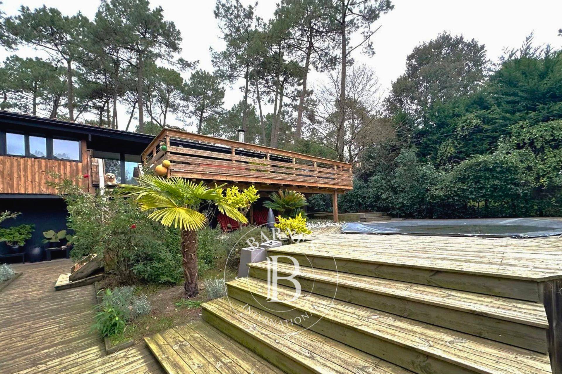 Pièce de vie lumineuse avec baies vitrées et terrasse en bois - Barnes Bassin d’Arcachon.